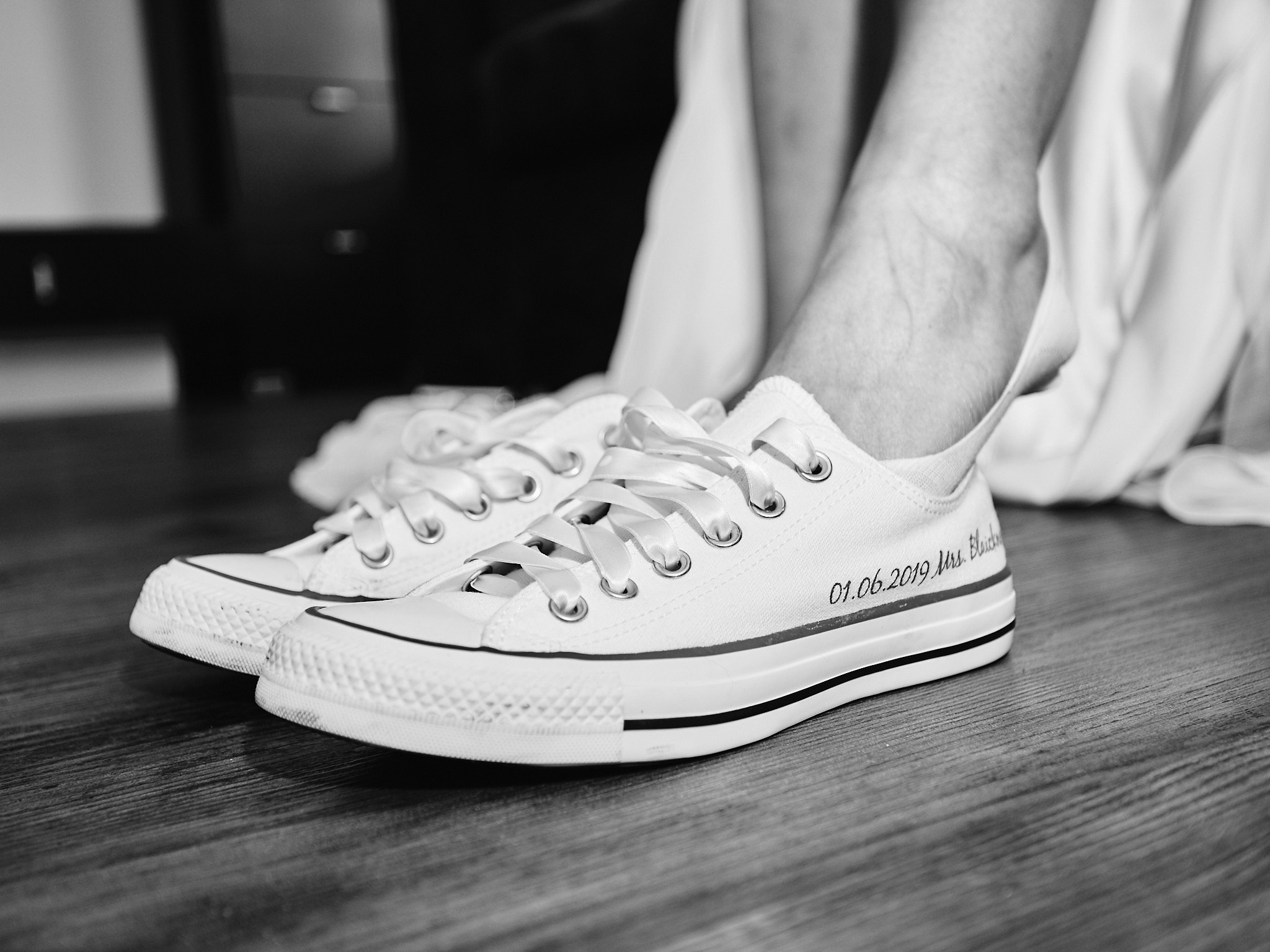 Braut zieht Hochzeitsschuhe an. Converse.